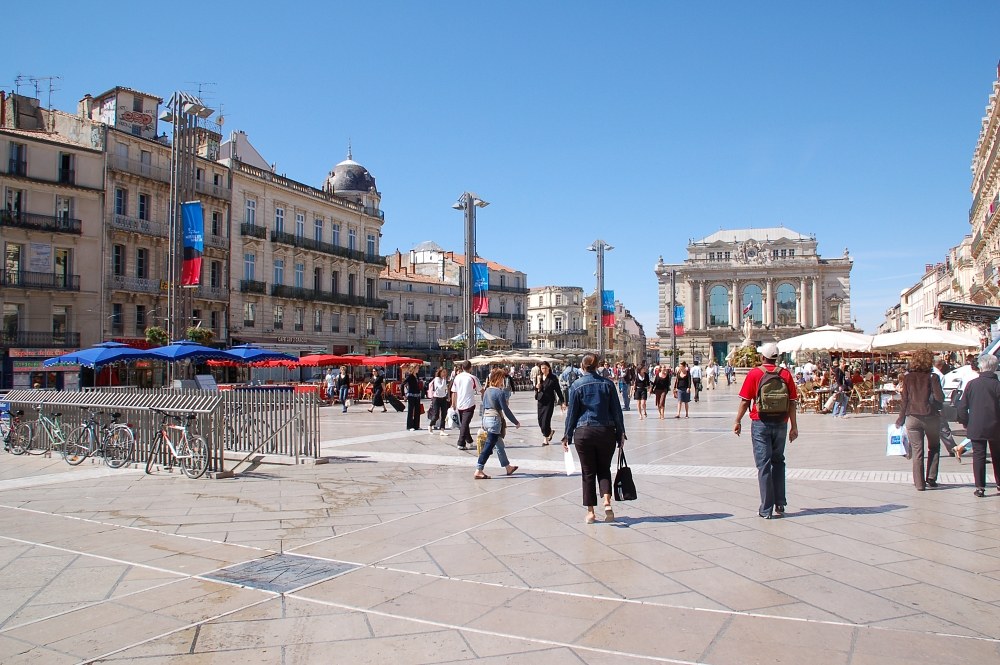 Place de la Comédie à Montpellier : dallage, terrasses, Opéra Comédie au fond, cyclistes et piétons.